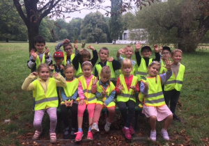 Grupowe zdjęcie dzieci siedzących w parku.