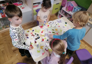 Grupa dzieci siedząca przy stoliku wycinająca cyfrę 6.