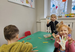 Dzieci siedzące przy stoliku wykonujące pracę plastyczną.
