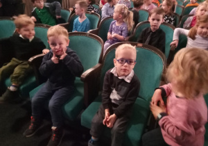 Dzieci siedzące na krzesłach w teatrze.