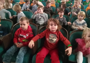Dzieci siedzące na krzesłach w teatrze.