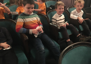 Dzieci siedzące na krzesłach w teatrze.