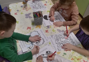 Dzieci siedzące przy stoliku kolorujące pracę.