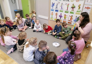 Dzieci siedzące na dywanie podczas zajęć.