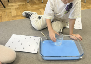 Chłopiec szukający liter pod wodą.