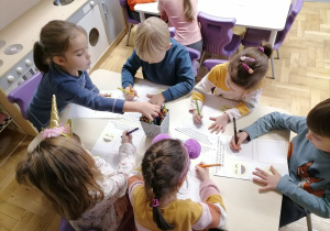Dzieci wykonujące pracę plastyczną przy stoliku.