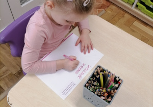 Dzieci wykonujące pracę plastyczną przy stoliku.