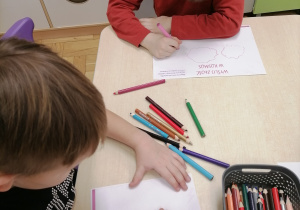 Dzieci wykonujące pracę plastyczną przy stoliku.