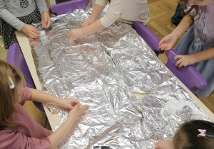 Dzieci bawiące się lodem i śniegiem na folii aluminiowej.