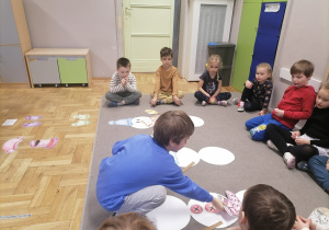 Dzieci układające bałwany na dywanie.