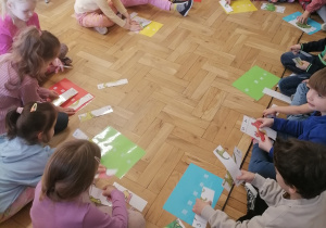 Dzieci układające puzzle z dinozaurami.
