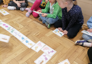 Dzieci układające domino z dinozaurami.