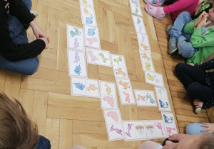 Dzieci układające domino z dinozaurami.