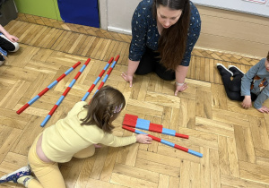 Dziewczynka układająca belki Montessori