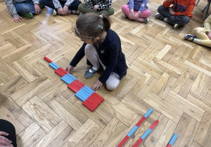 Dziewczynka układająca belki Montessori