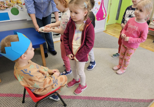 Dziewczynka składająca życzenia urodzinowe chłopcu w koronie.