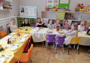 Dzieci w eleganckich strojach siedzące przy wielkanocnym stole.