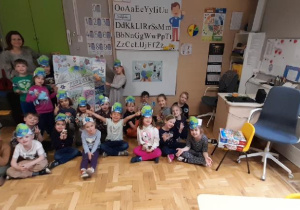 Grupa dzieci i nauczyciel z plakatem wykonanym przez dzieci z okazji Dnia Ziemi