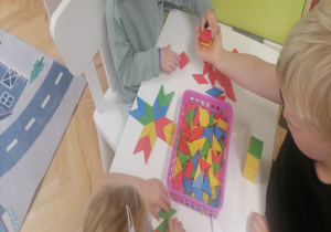Dzieci przy toliku układają figury geometryczne