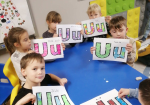 Dzieci prezentują pracę z wyklejanymi literami U