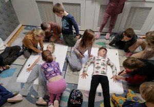 Dzieci obrysowują kolegę i koleżankę