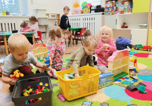 Dzieci bawią się na dywanie różnorodnymi zabawkami
