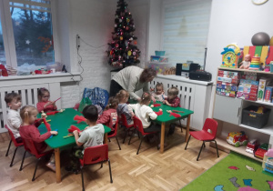 Dzieci wraz z Panią wykonują Mikołaja z kolorowych sznurków