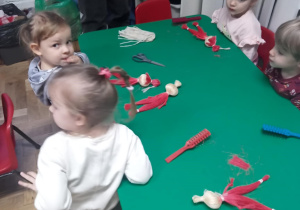 Dzieci siedzą przy stoliku przy swoich pracach