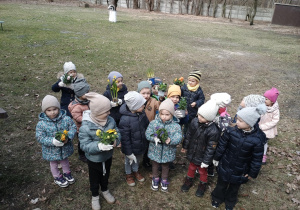 Dzieci pozują do zdjęcia z kwiatami w ogrodzie