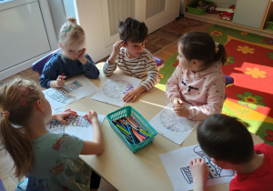 Dzieci przy stolikach kolorują skarpety