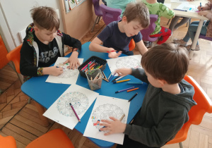 Dzieci przy stolikach kolorują mandale skarpetkowe