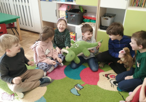 Dzieci na dywanie z zabawkowym dinozaurem