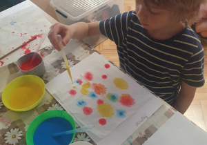 Chłopiec koloruje chusteczkę przy pomocy pipety