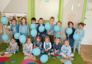 Dzieci ubrane na niebiesko pozują do zdjęcia z niebieskimi balonami