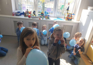 Dzieci dmuchają niebieskie balony