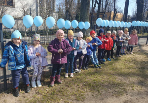 Dzieci w rzędzie pozują do zdjęcia w ogrodzie
