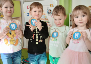 Dzieci trzymają w rękach odznaki białego ząbka