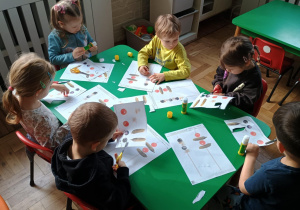 Dzieci wycinają ilustracje z owocami i warzywami