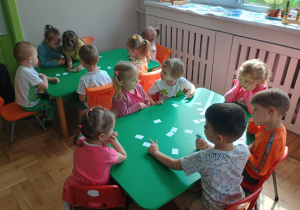 Dzieci siedzą przy stolikach i grają w memory