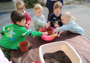Dzieci wsypują piasek do doniczki