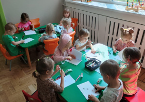 Dzieci siedzą przy stoliku i projektują swoją książkę