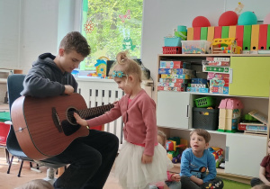 Dziewczynka próbuje grać na gitarze