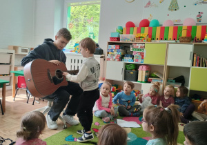Chłopiec próbuje grać na gitarze