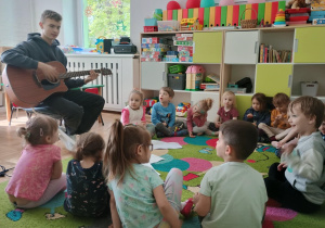Dzieci słuchają gry na gitarze