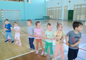 Dzieci na sali gimnastycznej ciągną linę