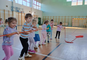 Dzieci na sali gimnastycznej ciągną linę