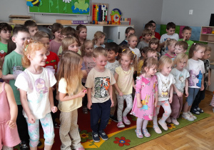 Dzieci stoją na dywanie, żywo reagując na polecenia aktorów