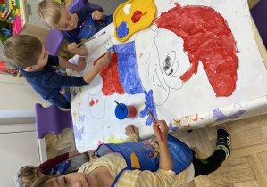 Dzieci malujące farbami bajkową postać Pappy Smerfa.