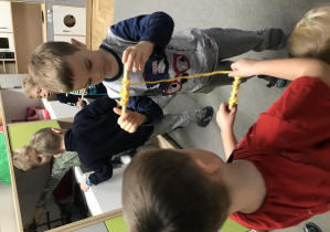 Dwaj chłopcy nawijąjący sznurek na patyczki.