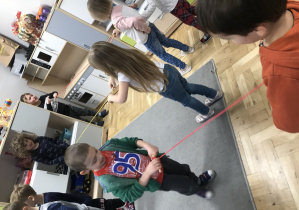 Grupa dzieci podczas zawodów nawlekających sznurki.